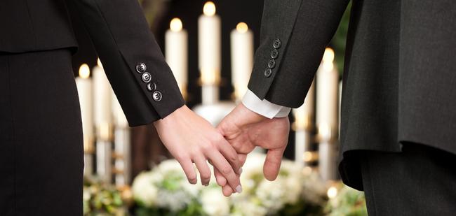 Hände eines Paares halten sich, umgeben von Kerzen und Blumenarrangements, in festlicher Atmosphäre.